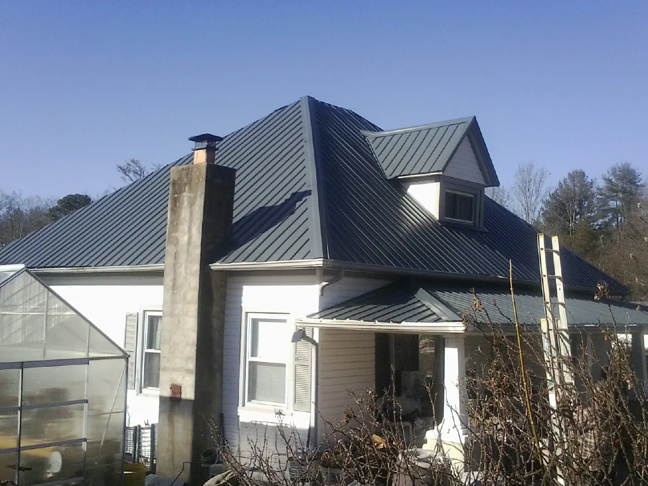 Dark blue standing seam metal roof on a white farmhouse with dormer — Slate & Tile Roof Repair by Roofing Brothers in White Swan