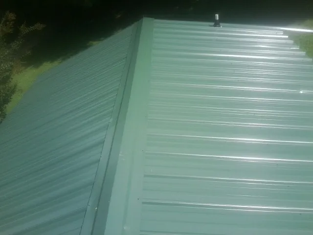 New green metal panels meeting at the ridge of a roof — Flat Roof Repair work by our crew in White Swan