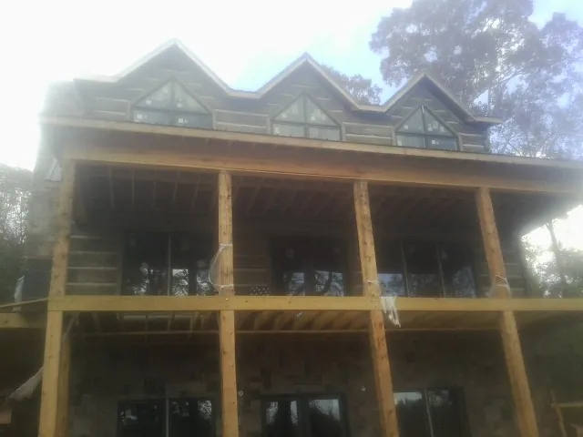 Dormers and porch framing on a large log home under construction — Roof Coating work by our crew in White Swan