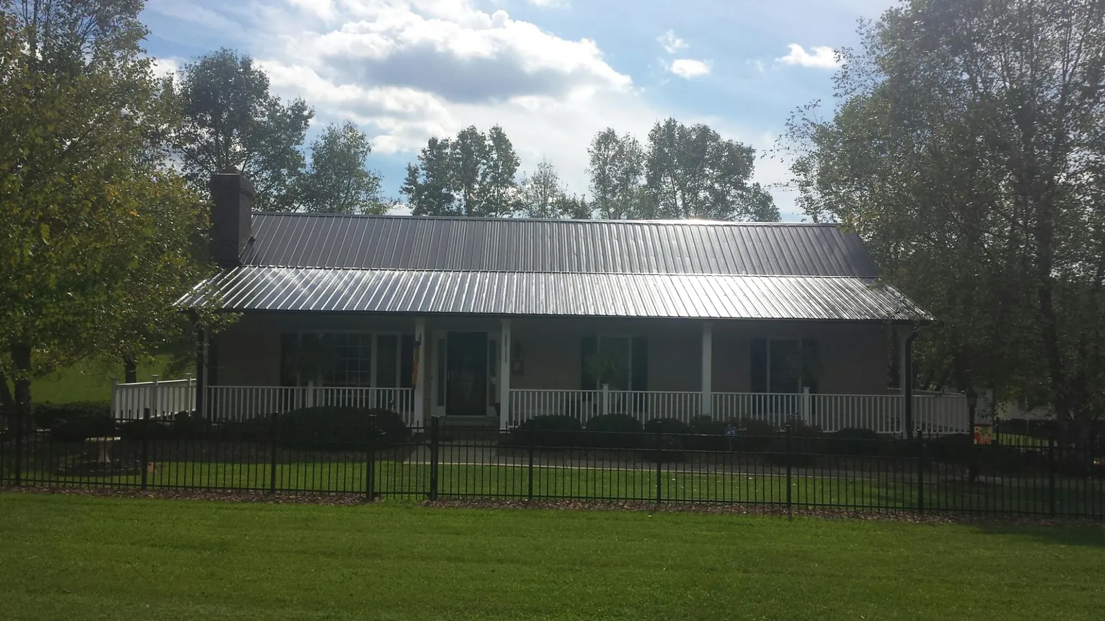 Gray metal roof on a brick ranch with a full width front porch — Gutter Guard Installation work by our crew in White Swan