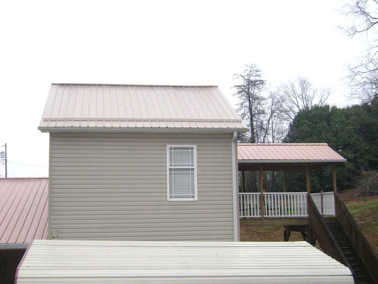 Tan metal roofs on a two story addition and attached porch, from a Roof Replacement job in White Swan