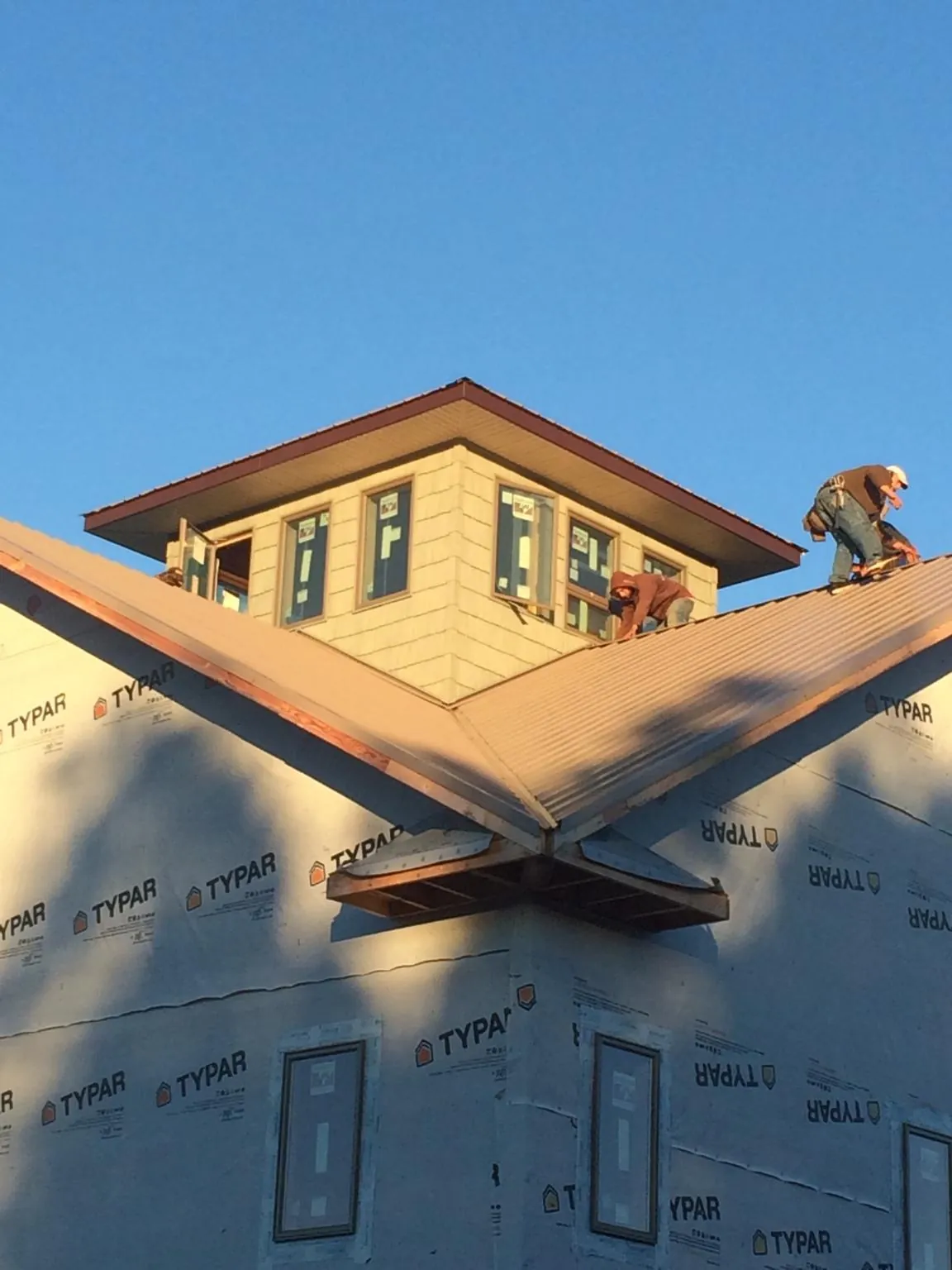 Roofers working around a rooftop cupola on a new metal roof at sunset — Roof Waterproofing in White Swan by Roofing Brothers